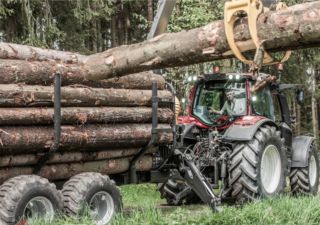 Valtra tractor with Kesla trailer in the forest loading timber.